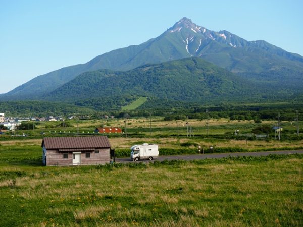 利尻島富士野園地から利尻山とキャンピングカーの画像、エゾカンゾウが咲いている